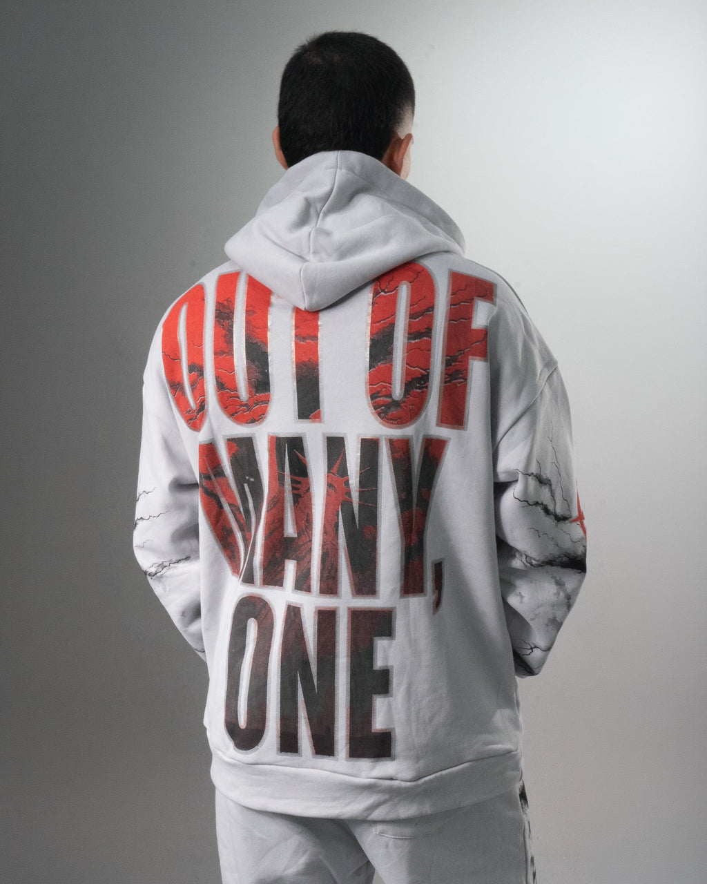 Espalda del buzo gris del conjunto Liberty con la frase OUT OF MANY, ONE en letras rojas